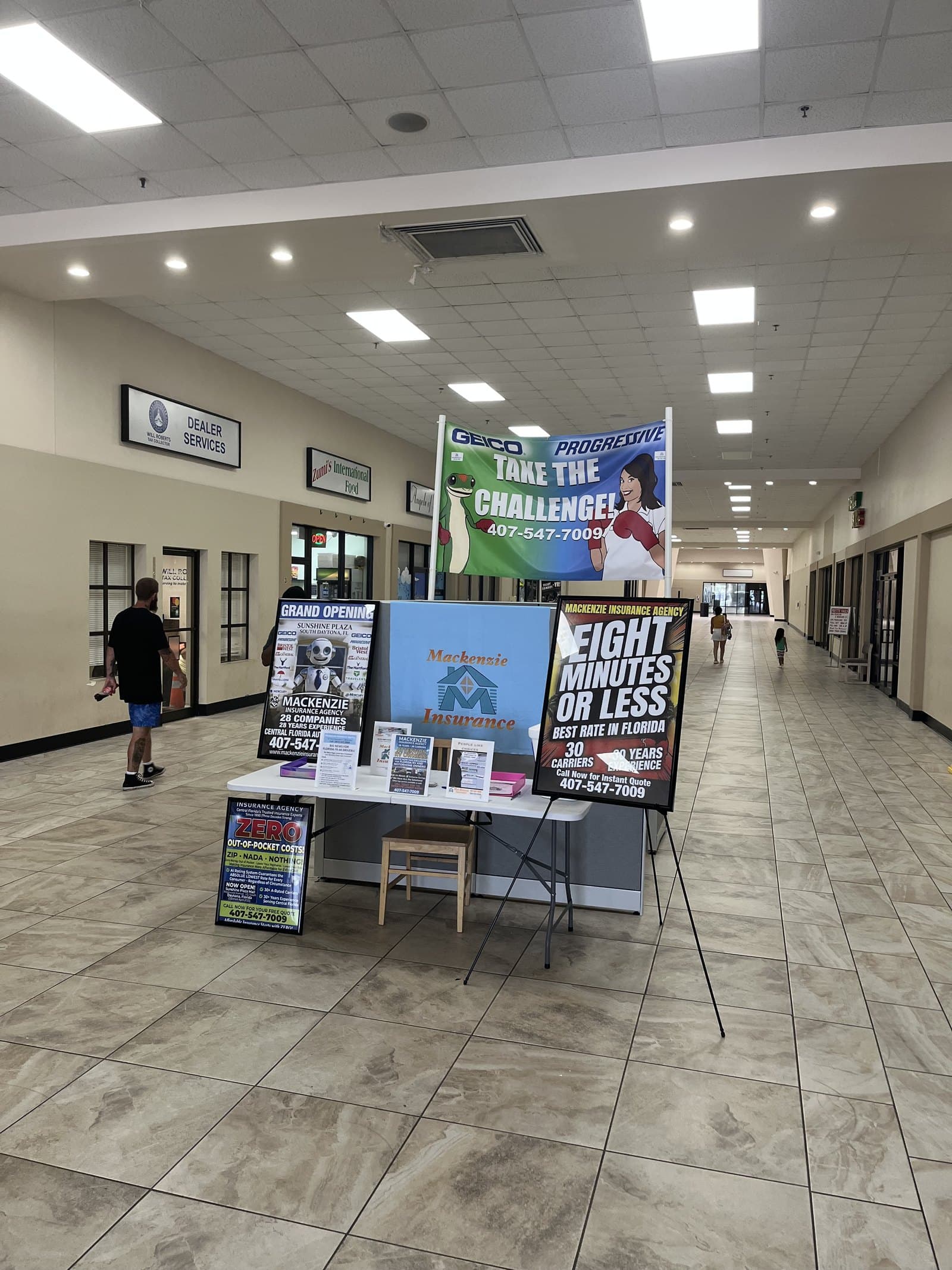 A staffed MacKenzie Insurance kiosk inside a busy Florida lobby